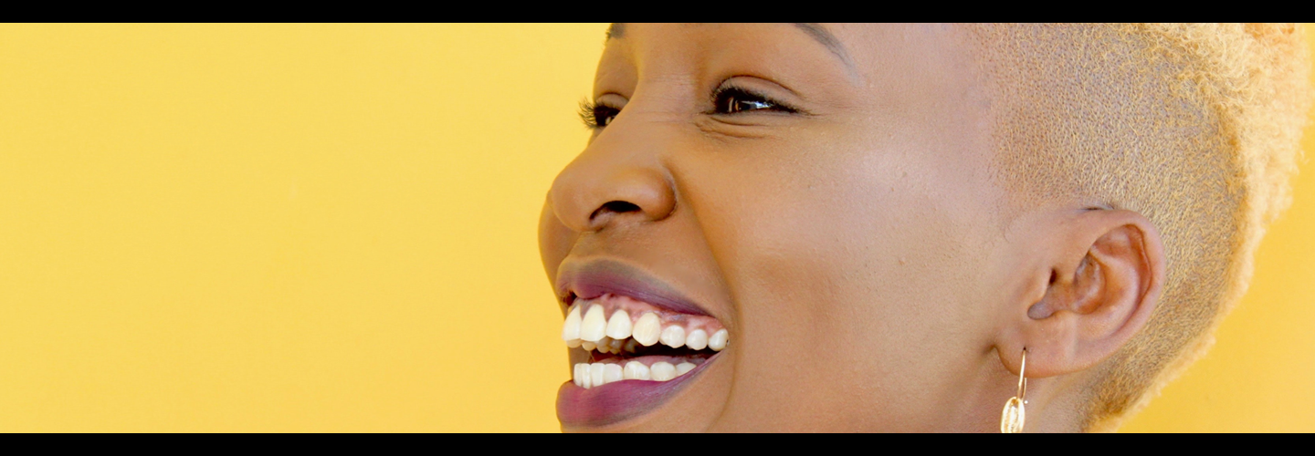 Profile view of woman laughing, against a yellow background