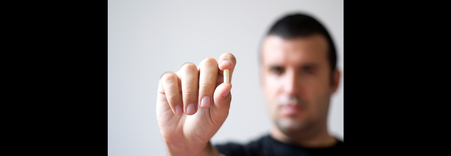 a man holding up a small white capsule in his hand